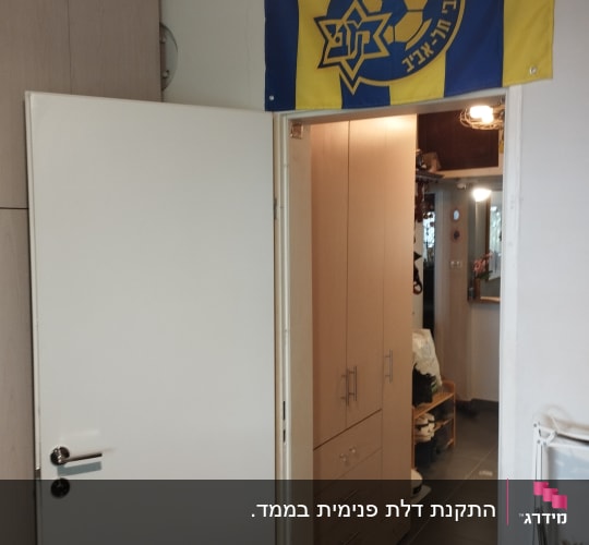 דלת לבנה פתוחה עם דגל תלוי מעליה